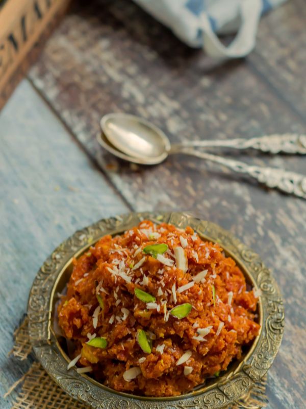 Gajar ka halwa in an engraved brass bowl topped with khoya and pistachios — Pakistani dessert recipe